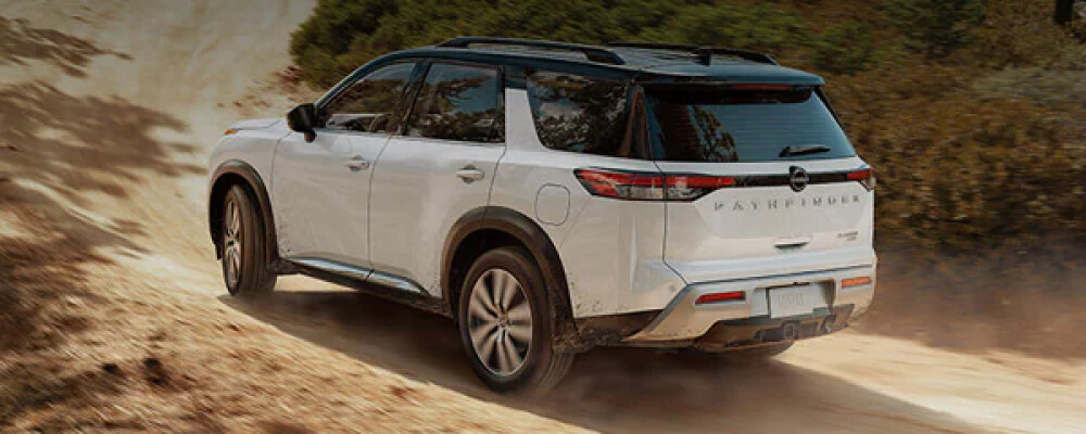 A white 2022 Nissan Pathfinder drives down a dirt road
