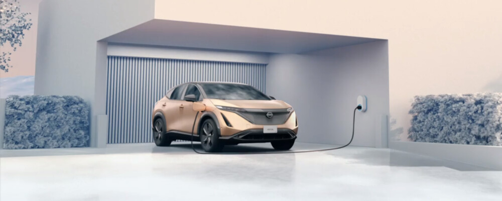 A 2023 Nissan Ariya is parked outside a home charging.