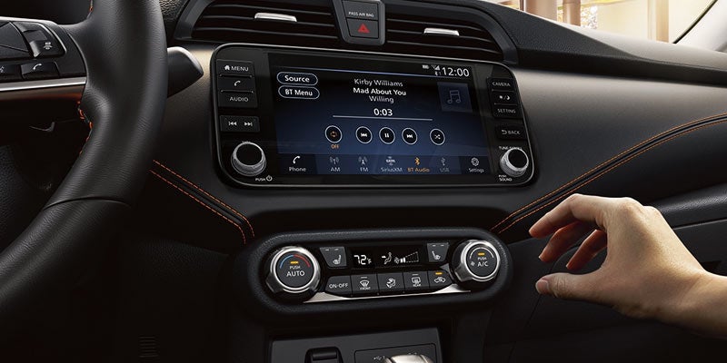 A hand reaching out to change the temperature in the 2024 Nissan Versa in Medina, OH